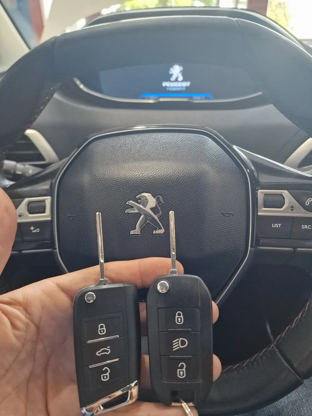 Dos llaves de Peugeot con mando junto al volante del coche